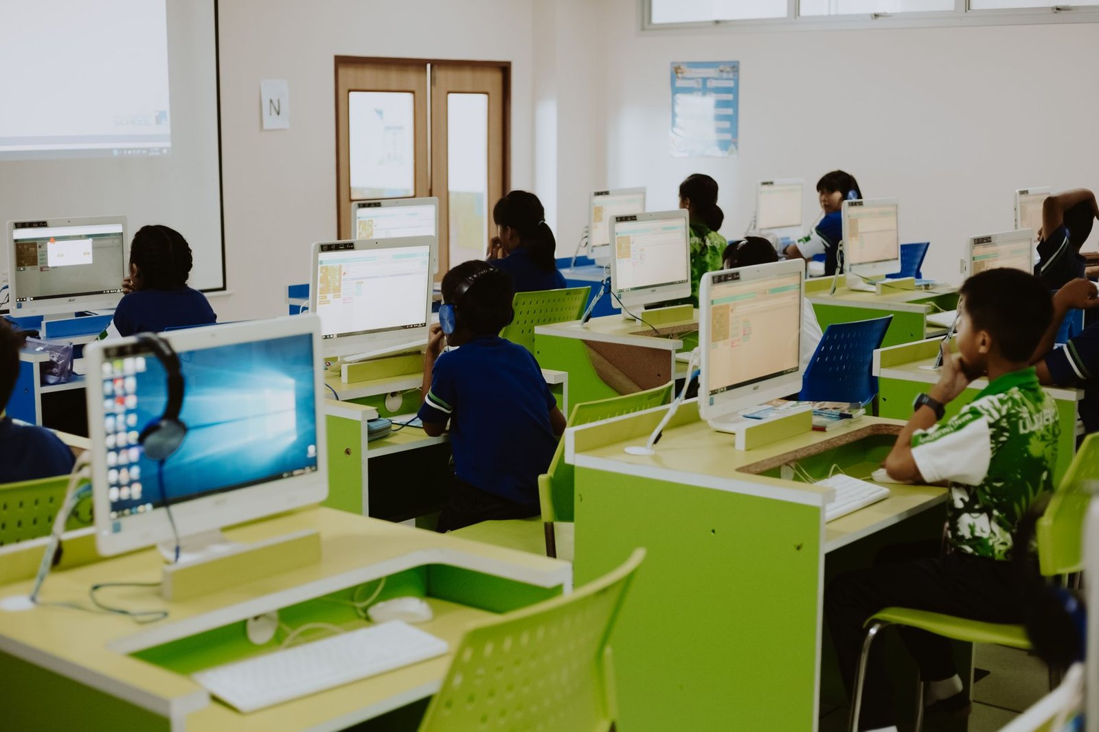 Classe d'enfants en cours de code en présentiel, en salle informatique