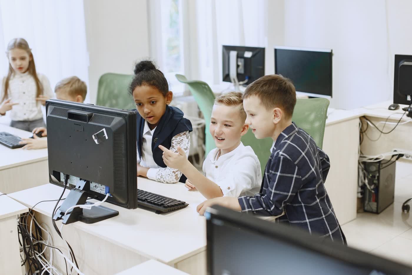 Enfants en train d'apprendre à coder sur ordinateur en salle informatique
