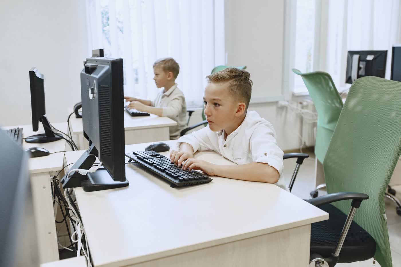 Deux jeunes élèves concentrés sur leur ordinateur pendant un cours de code